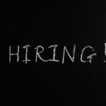 Close-up of the word 'Hiring!' written in white chalk on a blackboard, ideal for recruitment themes.